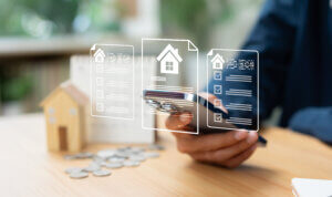 Investor reviewing property loan documents on a smartphone beside a model house, representing multifamily bridge loan underwriting